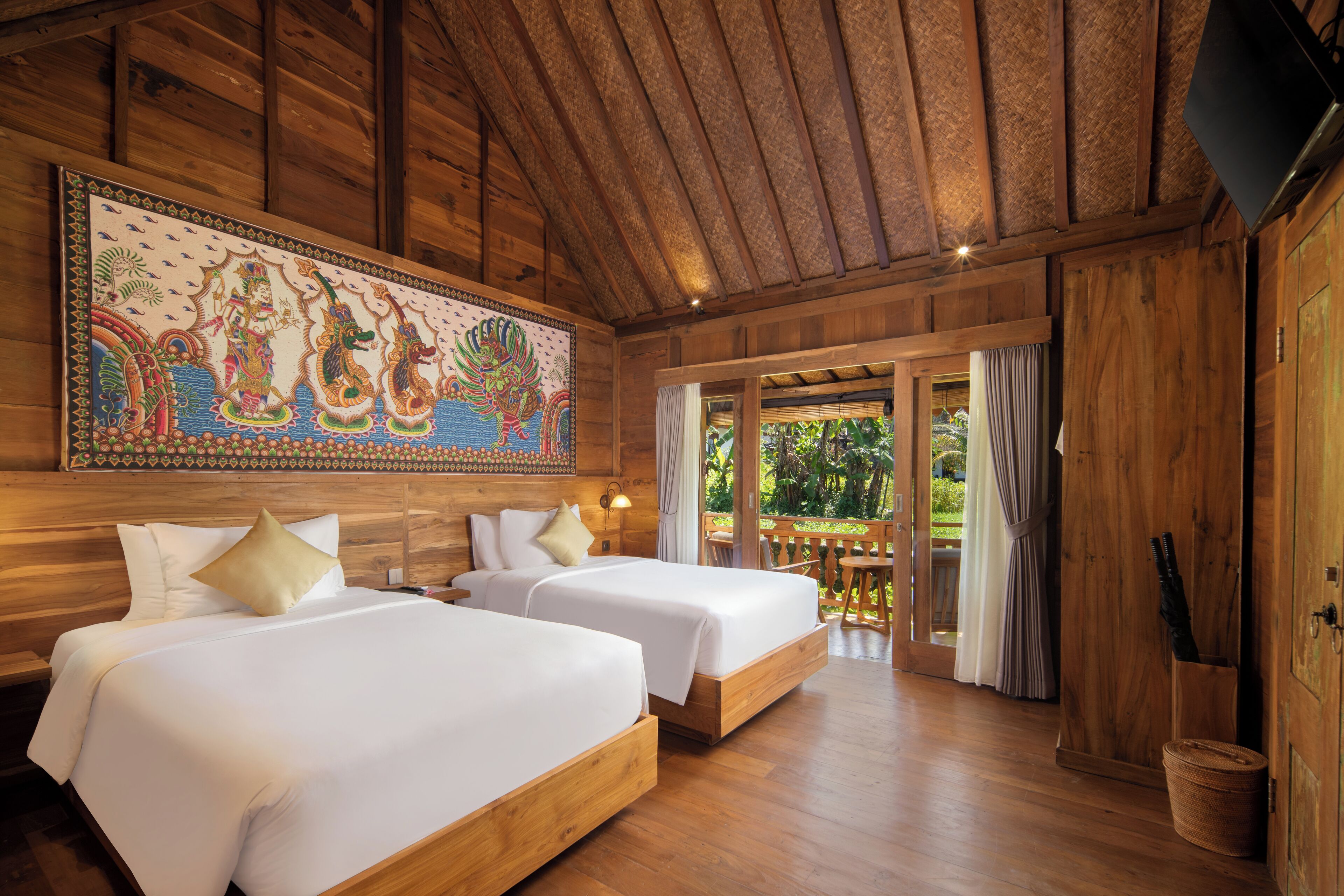 A wooden cabin with two beds, a large mural, and a balcony with curtains.