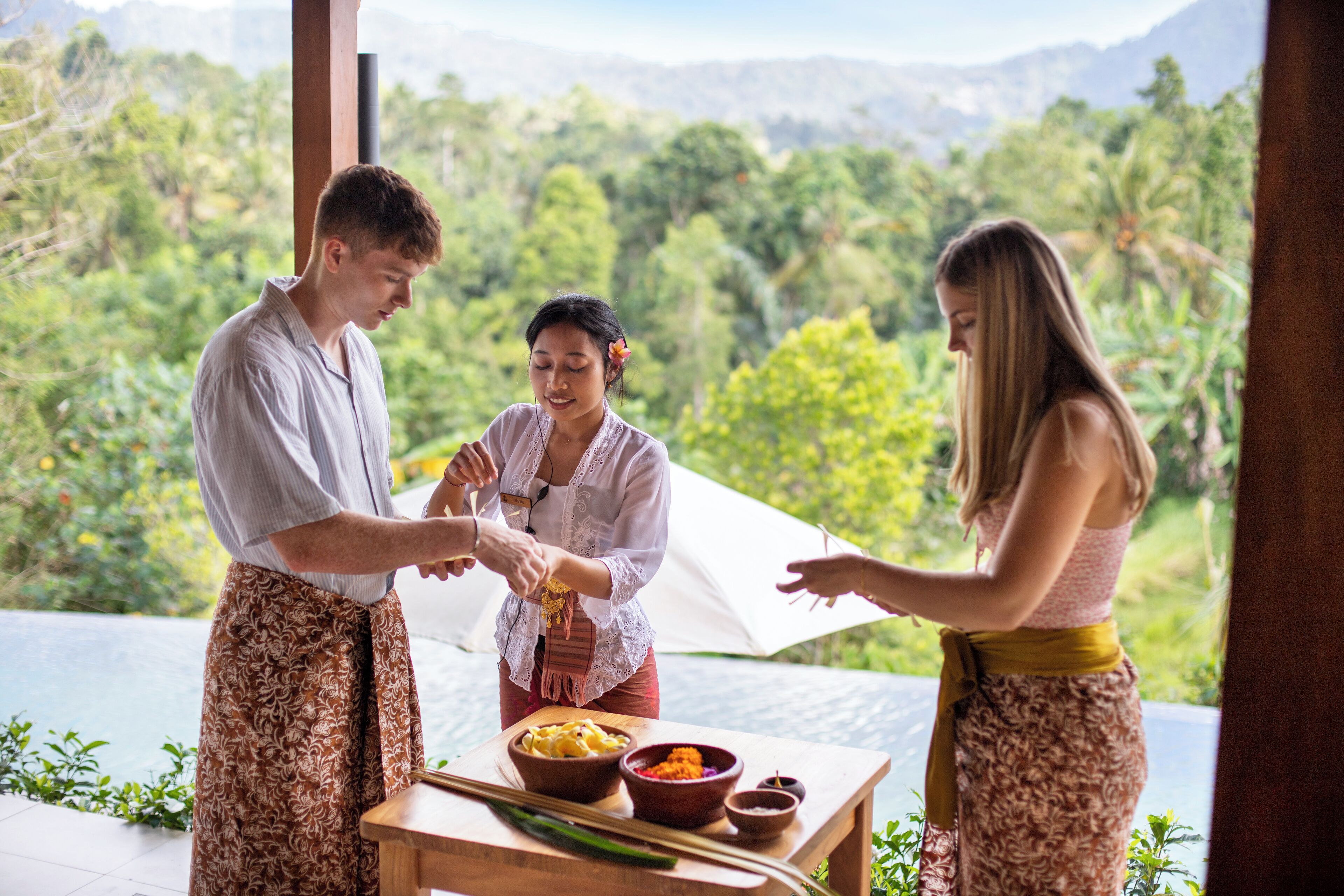 A group of people preparing food outdoors with a scenic view of lush greenery and mountains in the background.