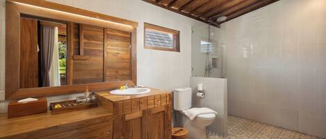 A bathroom with a wooden vanity, a sink, a toilet, and a shower area.