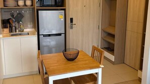 Eine kleine Küche mit Holzausstattung, einem Edelstahlkühlschrank und einem Esstisch mit Stühlen.