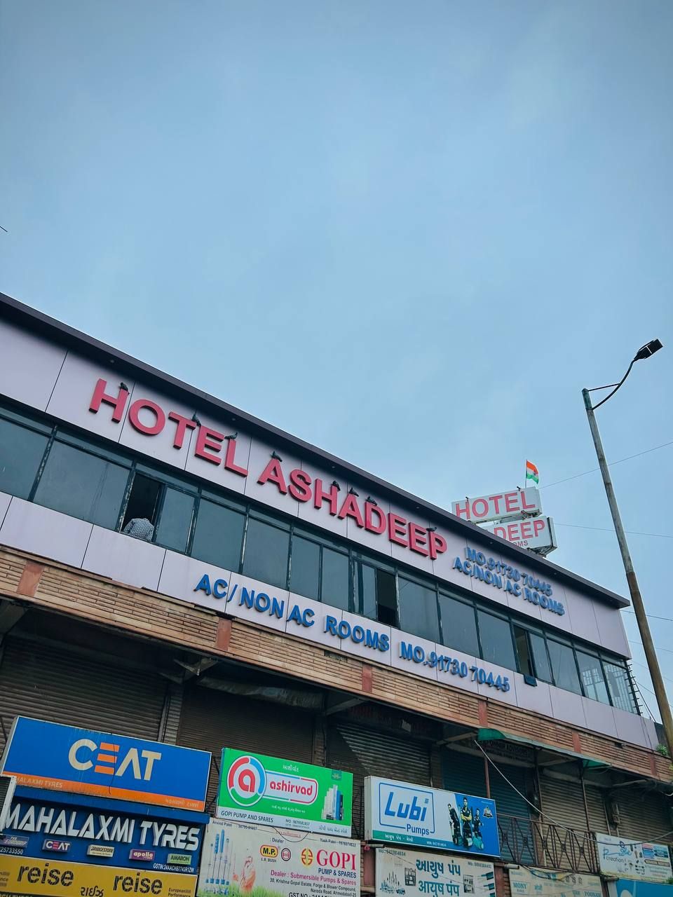 A hotel named "HOTEL ASHADEEP" with AC/Non AC rooms and various local business advertisements.