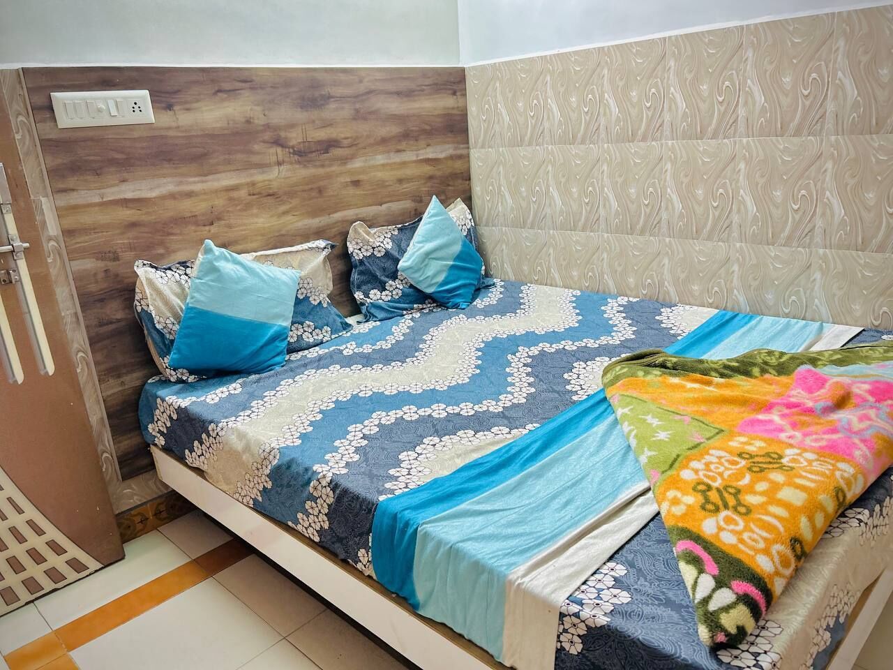 A bedroom with a wooden headboard, a patterned bedspread, and a colorful blanket.