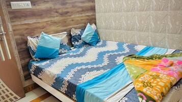 A bedroom with a wooden headboard, a patterned bedspread, and a colorful blanket.