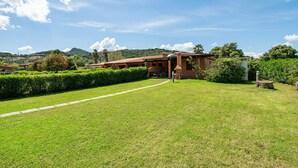 Una casa con jardín y una montaña al fondo.