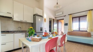 Una cocina con armarios blancos, un refrigerador de acero inoxidable y una mesa de comedor con mantel blanco.