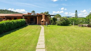 Una casa con un sendero empedrado que lleva a la entrada, rodeada de césped y setos cuidados.