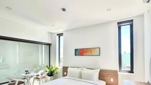 Una habitación de hotel moderna con una cama grande, un escritorio y una silla. Hay una ventana con vista a la ciudad.