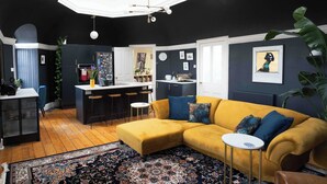 Una sala de estar moderna con un sofá amarillo, una mesita redonda y una alfombra estampada.