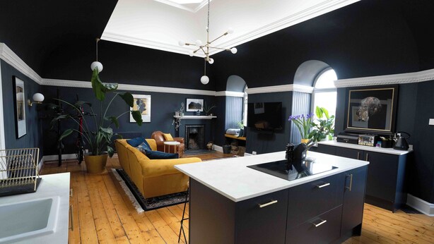 Una sala de estar moderna con un sofá amarillo, chimenea y una isla de cocina.