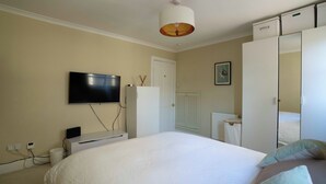 Un dormitorio con cama, televisor en la pared, armario y radiador.