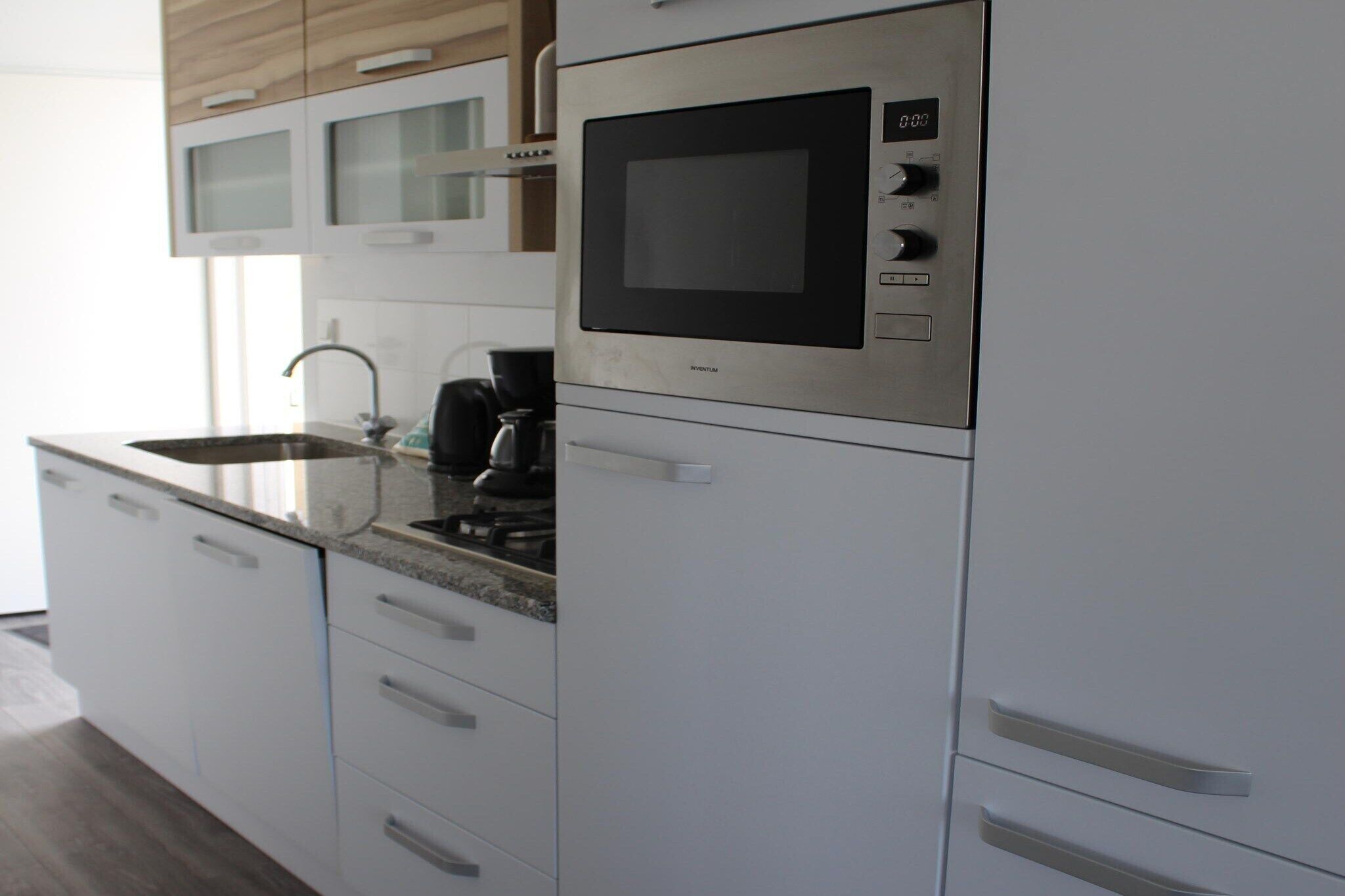 Una cucina moderna con elettrodomestici in acciaio inossidabile, forno integrato e macchina da caffè.