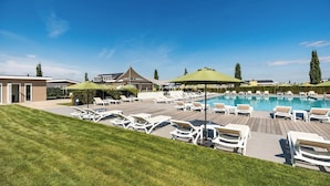 A pool area with lounge chairs and umbrellas, surrounded by a wooden deck and a well-maintained lawn. - Chalet in Bemelen near Bemelerberg Reserve (Bemelen)