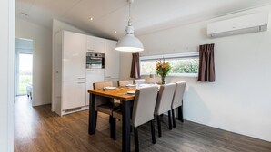 A modern kitchen with white cabinets, a built-in oven, and a dining area with a wooden table and chairs.