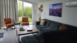 A modern living room with a sofa, two armchairs, a coffee table, and a large window with curtains. - Holiday Home Bemelen near Nature Reserve (Bemelen)