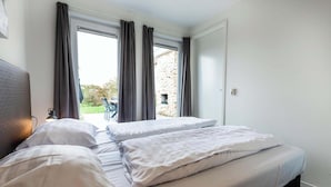 A bedroom with a bed, curtains, and a view of the outdoors.