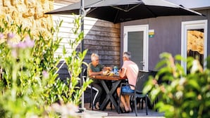 An outdoor dining area with a stone wall, a wooden fence, and a door labeled "67".