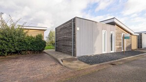 Een modern gebouw met een plat dak, een deur en een bord met een aanduiding van een locatie.