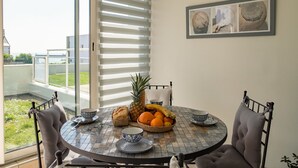 A dining area with a round table, chairs, and a view through a glass door. - Entre port et plages by Interhome (Audierne)