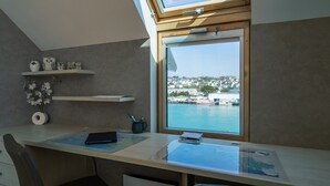 A modern office space with a desk, chair, and a large window overlooking a harbor. - Entre port et plages by Interhome (Audierne)
