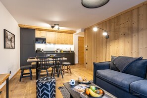 Et moderne køkken med træskabe, et spiseområde med bord og stole, og en opholdsstue med sofa og sofabord.