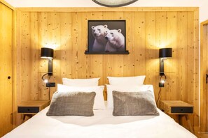 A wooden-paneled room with a bed, two nightstands, and a framed picture of polar bears.