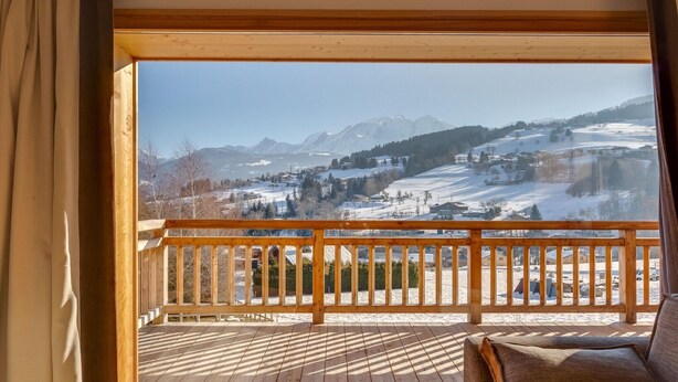 Een houten terras met uitzicht op een besneeuwd berglandschap.