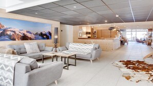 Een moderne woonkamer met een groot berglandschap, een zithoek, een salontafel en een kussen van runderhuid.