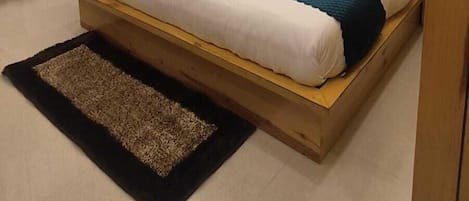 A hotel room with a large bed, a wooden headboard, a desk, a chair, and a ceiling fan.