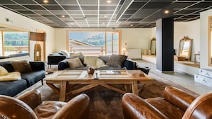 A modern lounge area with leather chairs, a wooden table, and sofas.
