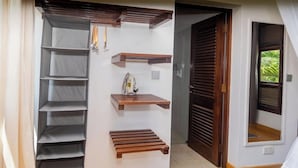 A room with a built-in wardrobe, a wooden bench, and a small shelf with a bag.