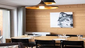 Un comedor con pared de madera, un cuadro grande de un lobo y una mesa dispuesta para cuatro personas con sillas.