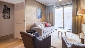 Una sala de estar moderna con un sofá, sillones, una mesa de centro y vistas a un paisaje nevado a través de amplios ventanales.