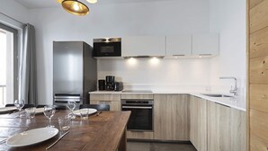 A modern kitchen with wooden cabinets, stainless steel appliances, and a dining area with a wooden table and chairs.