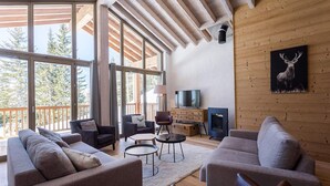 A spacious living room with a large window, a fireplace, and a mounted deer painting. - Apartment in La Rosière with Alpine Views (la rosiere montvalezan)