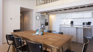 A modern kitchen with a wooden dining table, chairs, and a balcony with a railing. - Apartment in La Rosière with Alpine Views (la rosiere montvalezan)