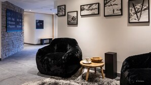 Eine moderne Lobby mit einer Steinwand, schwarzen Samtstühlen und gerahmten Schwarz-Weiß-Fotos an der Wand.