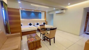 A modern hotel room with a bed, a sofa, a dining table with chairs, and a small wooden coffee table. - HOTEL PARQOTEL (Vapi)