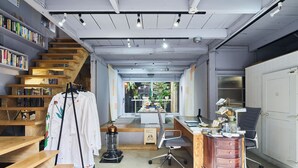 Un espace de bureau moderne avec un escalier en bois, des étagères, un bureau et une chaise.