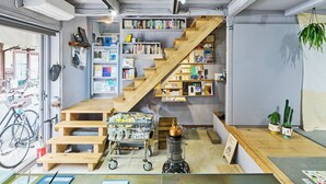 Un espace de travail accueillant et bien aménagé, avec un escalier en bois, des étagères, un vélo et différents postes de travail.