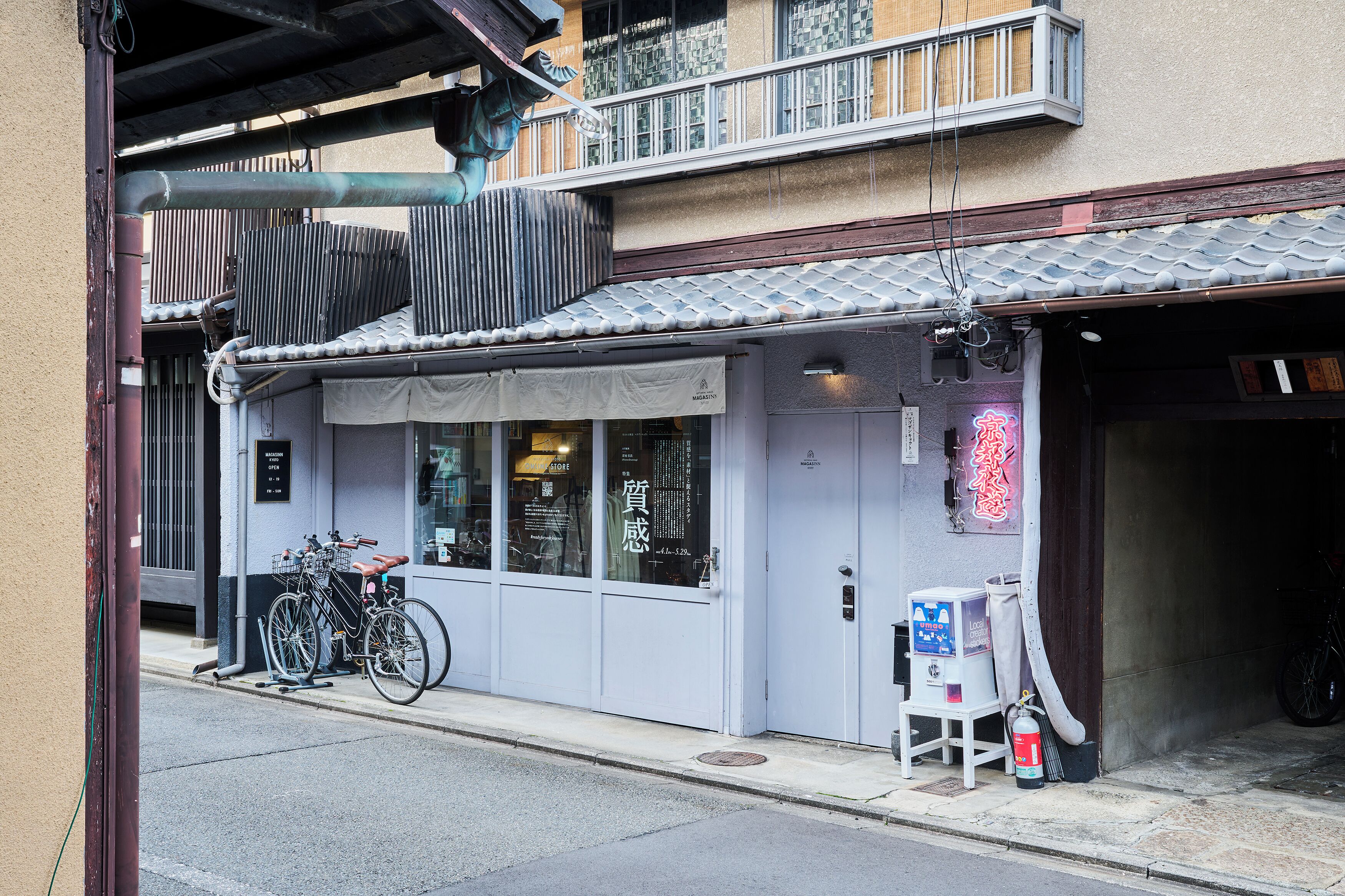 A building with a tiled roof, a bicycle parked outside, and a fire extinguisher on the sidewalk.