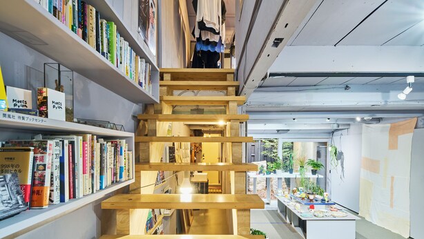 Une librairie à plusieurs niveaux, avec des étagères en bois et un escalier central.