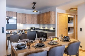 Une cuisine compacte avec des meubles en bois, une table à manger pour quatre personnes et un four encastré.