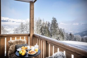 A wooden deck with a table set for breakfast, overlooking a snowy mountain landscape. - Apartment in Alps with Views (AIME-LA-PLANGE)