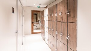 Un pasillo con taquillas, una puerta de madera y suelo de baldosas.