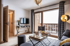 Una sala de estar moderna con una televisión, un escritorio de madera, un balcón con barandilla y un sofá.