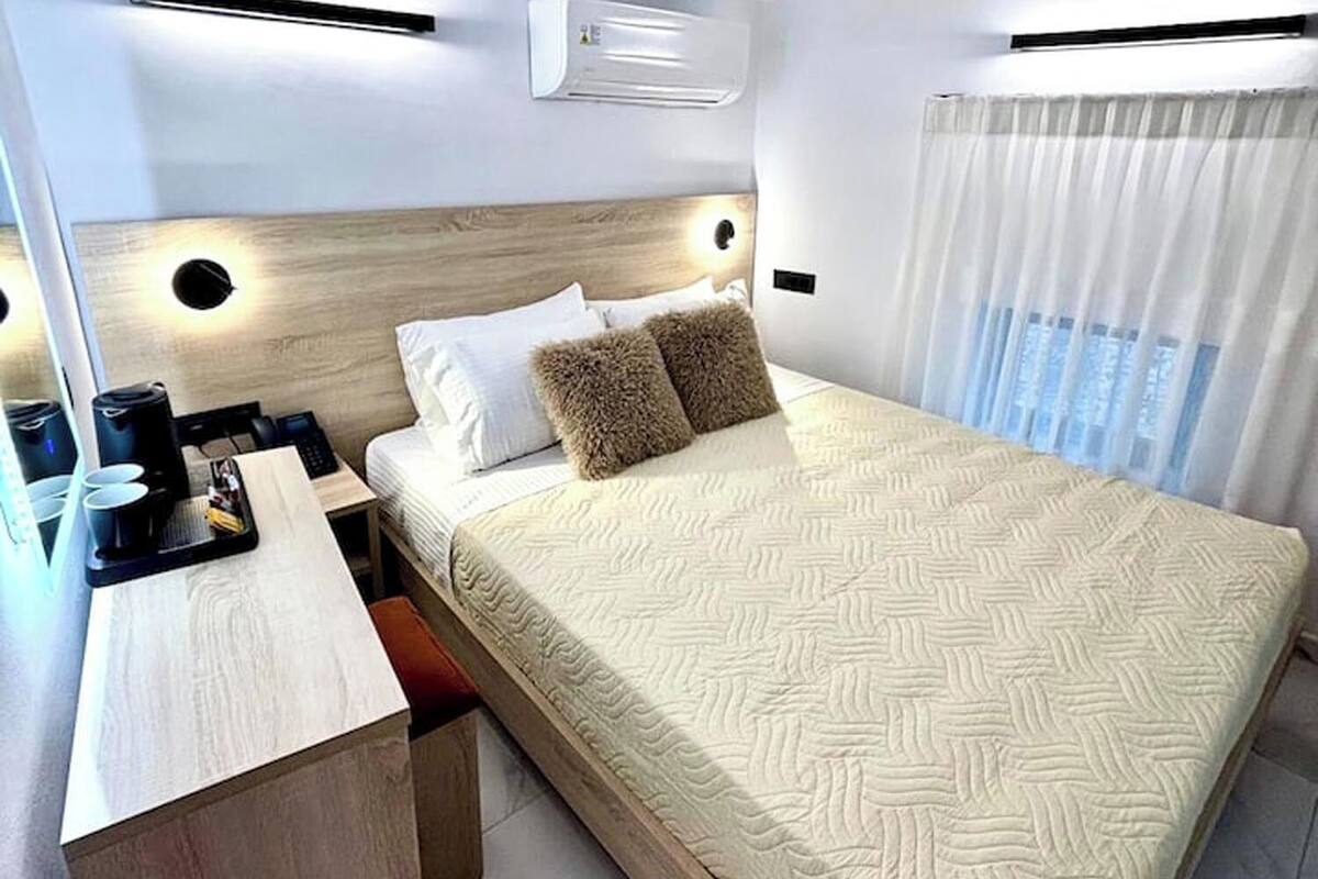 A modern hotel room with a bed, bedside table, and a desk with a coffee machine.