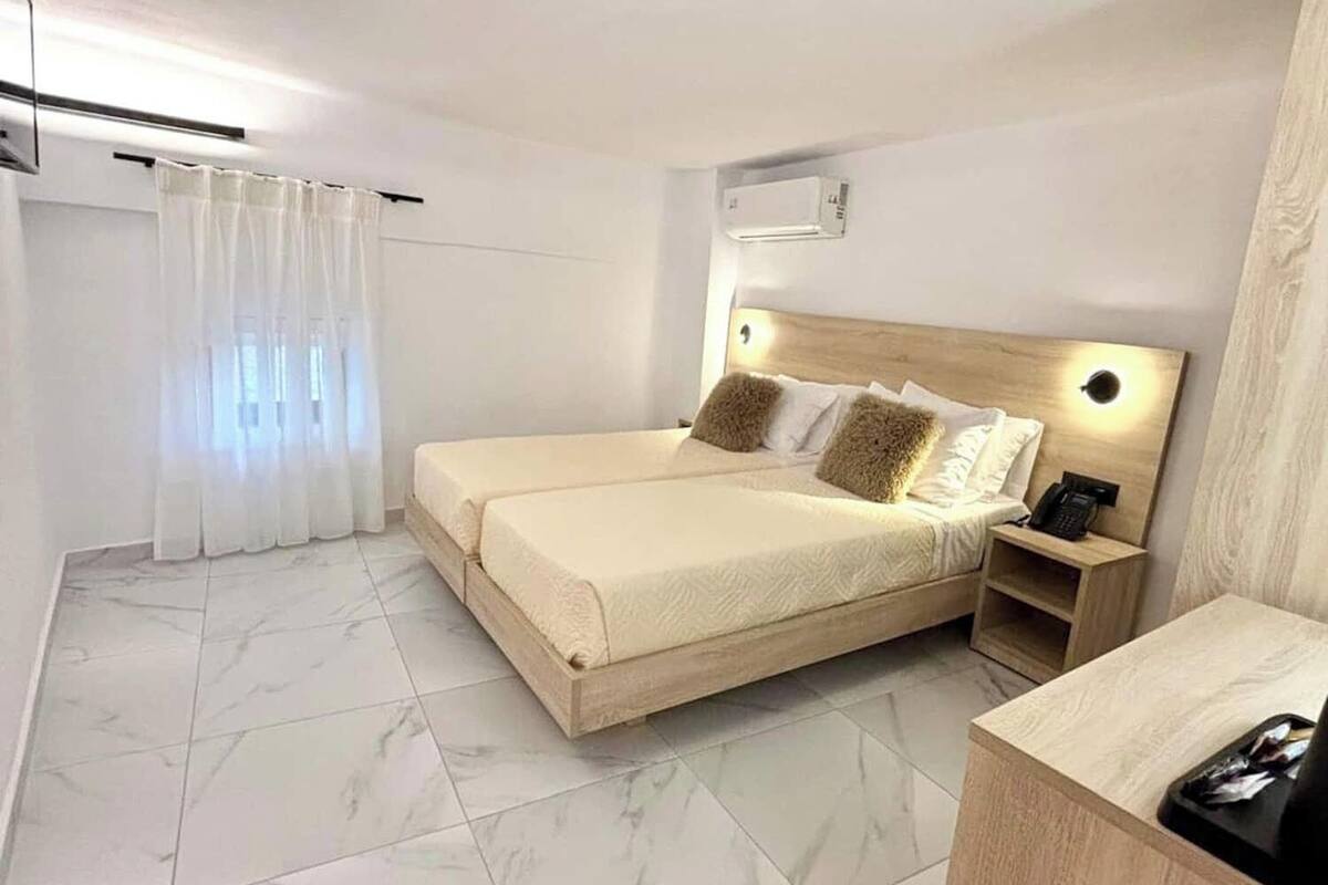 A modern hotel room with a large bed, a bedside table, and a small desk.