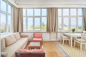 A sunroom with a sofa, a table, and chairs.