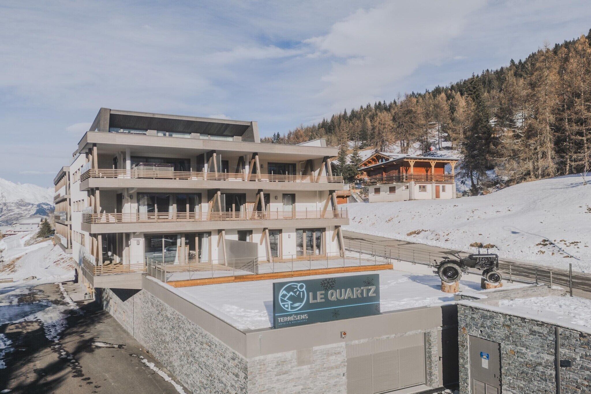 A multi-story hotel with a sign reading "LE QUARTZ TERRÈSENS" on the rooftop.