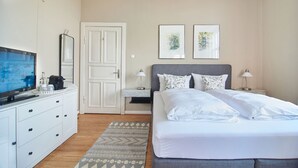 A hotel room with a bed, a TV, a desk, and a door. - Double room "Seestern" - Quiet time-out with sea view on the second floor - (Timmendorfer Strand)